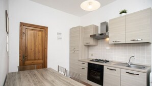Une cuisine moderne avec des meubles de couleur bois clair, une hotte en acier inoxydable, un four encastré et un évier.