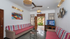 A living room with a sofa, a small table, a ceiling fan, and a television. - Villa Calangute Phase 1 (Calangute)