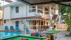 A pool area with a foosball table, pool table, and lounge chairs. - Villa Calangute Phase 1 (Calangute)