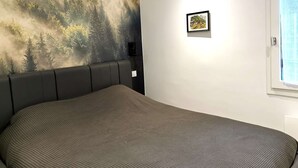 Una camera da letto con un letto, un affresco, un quadro incorniciato e una finestra.