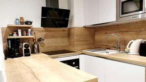 Una cucina moderna con piano di lavoro in legno, elettrodomestici in acciaio inossidabile e mobili bianchi.