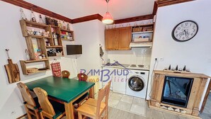 Una cocina compacta con una mesa de comedor, sillas, lavadora y televisor integrado.