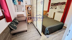 Un dormitorio con cama, sofá, armario y un escritorio pequeño.