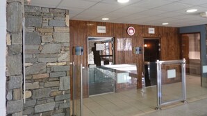 Un vestíbulo con pared de piedra, un mostrador de recepción y carteles que indican 'HAMMAM' y 'SAUNA'.