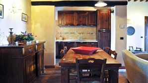 Une cuisine rustique avec des meubles en bois, un pare-feu en carreaux et un coin repas comprenant une table et des chaises en bois.