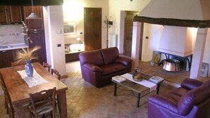 Un salon chaleureux avec un canapé en cuir marron, une table à manger avec des chaises et une cheminée.