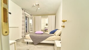 A bedroom with a bed, a bedside table, a wardrobe, and a sliding glass door leading to a balcony.