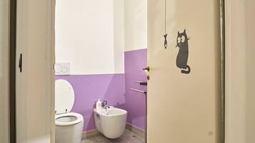 Un pasillo estrecho que conduce a un baño con inodoro, bidé y lavamanos.