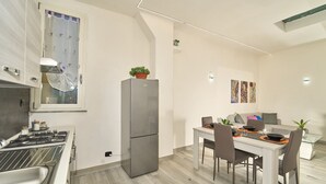 A modern kitchen with a gas stove, stainless steel refrigerator, and a dining area with a table and chairs.