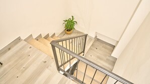 A staircase with a metal railing, beige wooden steps, and a potted plant on the landing.