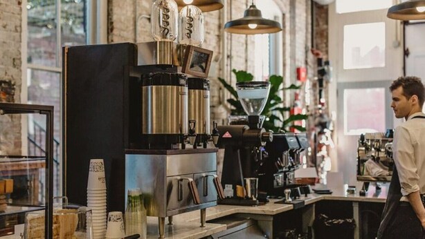 Kahvilan sisustus, jossa on espressokoneita, riippuvalaisimia ja suuri ikkuna.