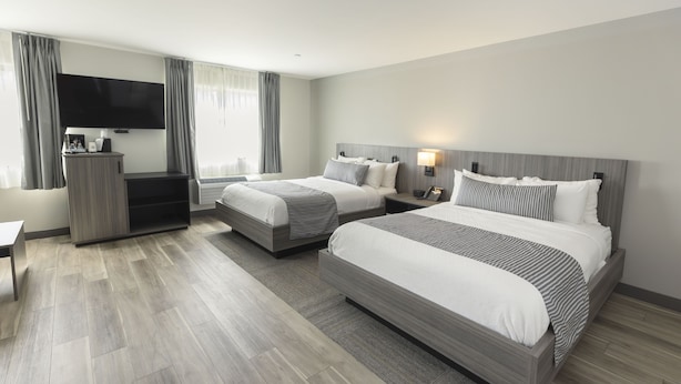 Una habitación de hotel con dos camas, televisión, escritorio y armario.