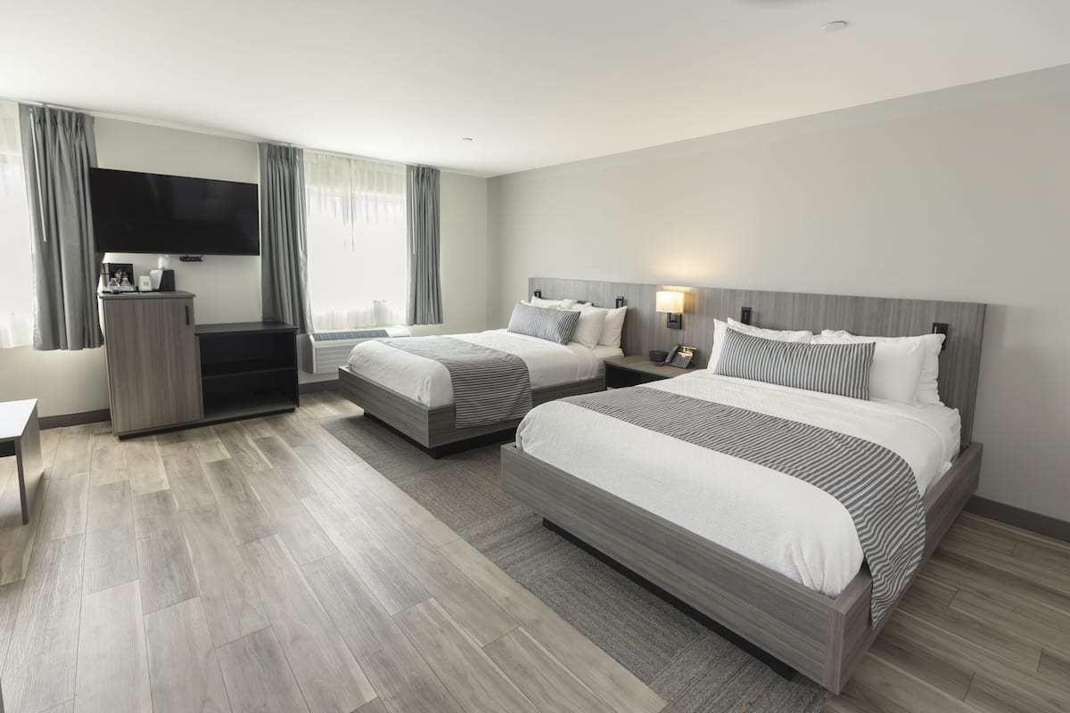 A hotel room with two beds, a TV, a desk, and a wardrobe.