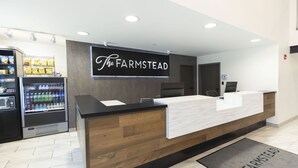 Una recepción con un cartel que dice "The FARMSTEAD", una máquina expendedora de aperitivos y un dispensador de agua.