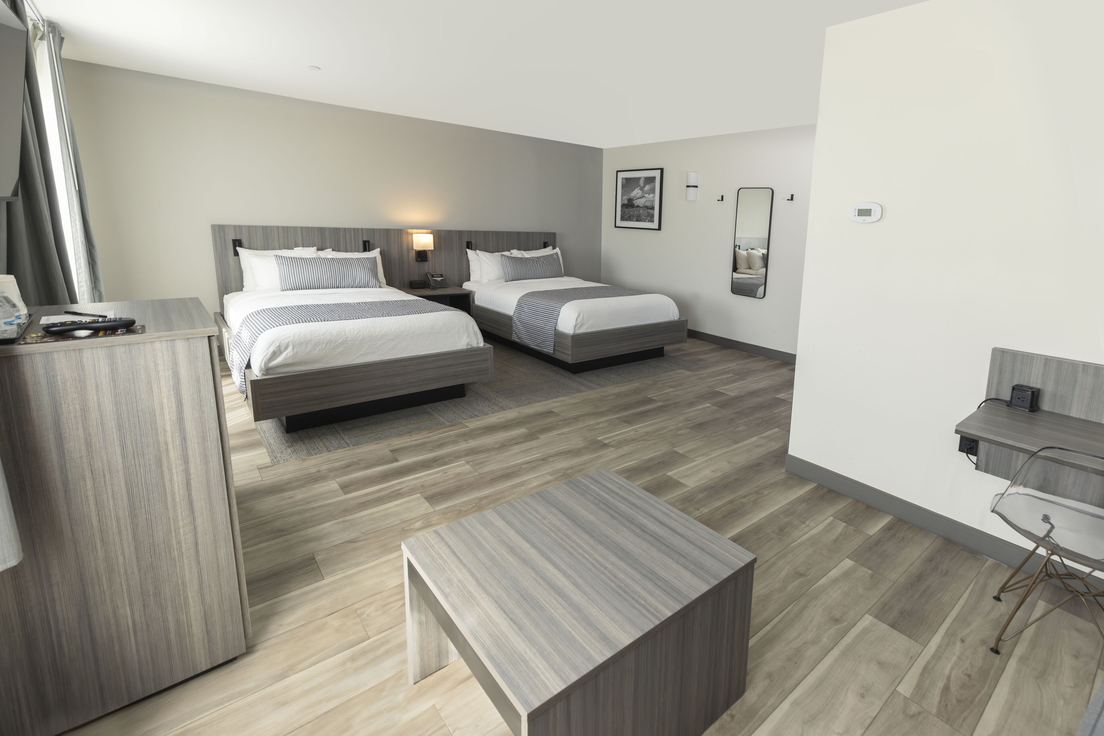 Een moderne hotelkamer met twee bedden, een bureau en een stoel.