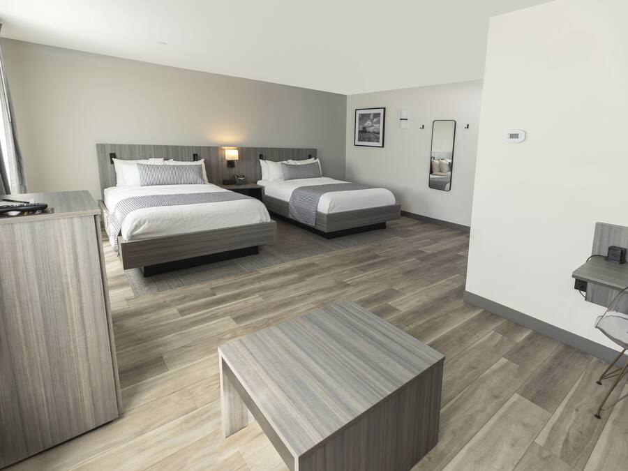Een moderne hotelkamer met twee bedden, een bureau en een stoel.