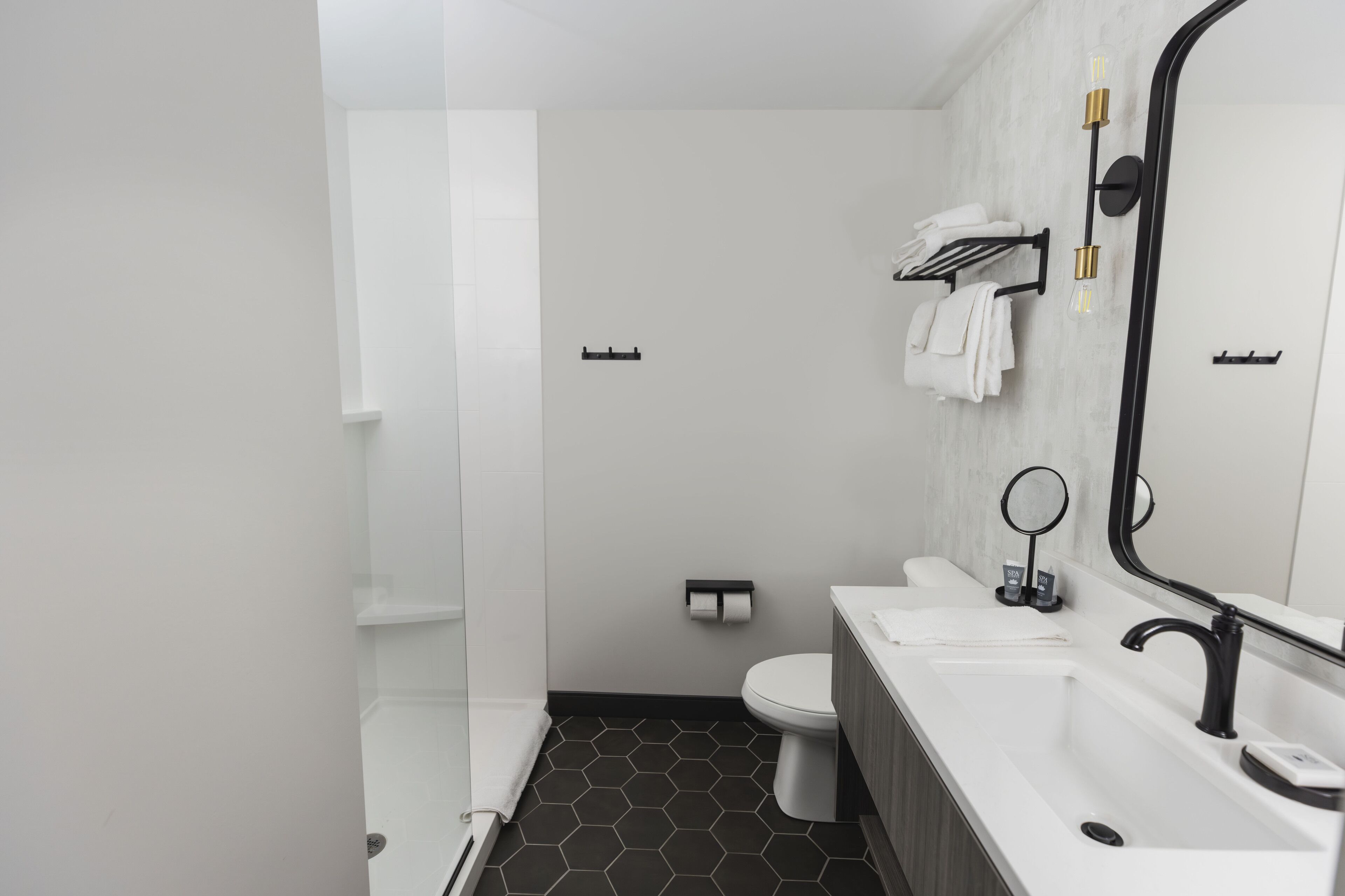 A modern bathroom with a white sink, black faucet, and a large mirror.