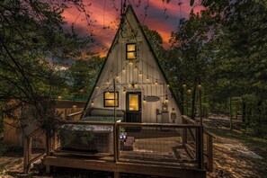 Une cabane en bois avec un toit en pente, une véranda et une petite terrasse.