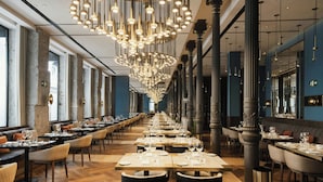 A long dining area with tables set for service, large windows on one side, and a modern chandelier. - JW Marriott Hotel Madrid (Madrid)