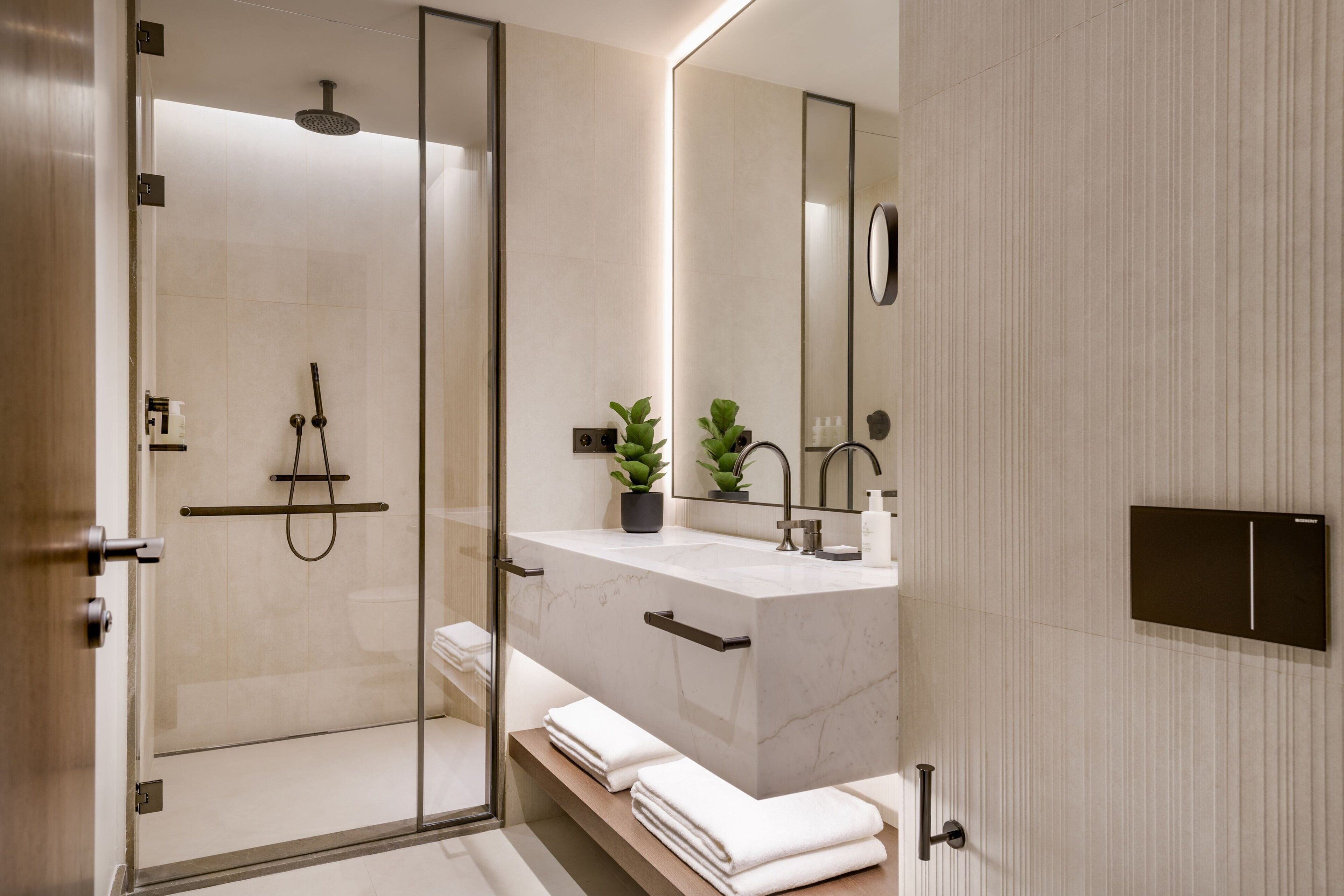 A modern bathroom with a glass-enclosed shower, a marble sink, and a large mirror.