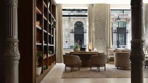 A spacious lobby with a large window, a fireplace, and a seating area with chairs. - JW Marriott Hotel Madrid (Madrid)