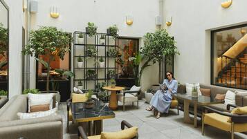 A spacious outdoor seating area with multiple tables and chairs, surrounded by potted plants and a staircase.