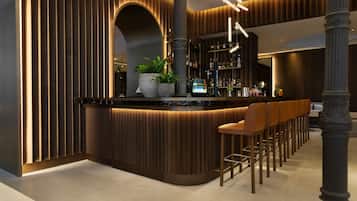 A modern bar area with a curved counter, multiple stools, and a potted plant.