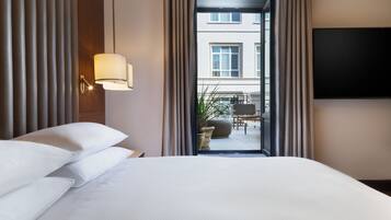 Een hotelkamer met een bed, een lamp, een televisie en uitzicht op het buitenbalkon.