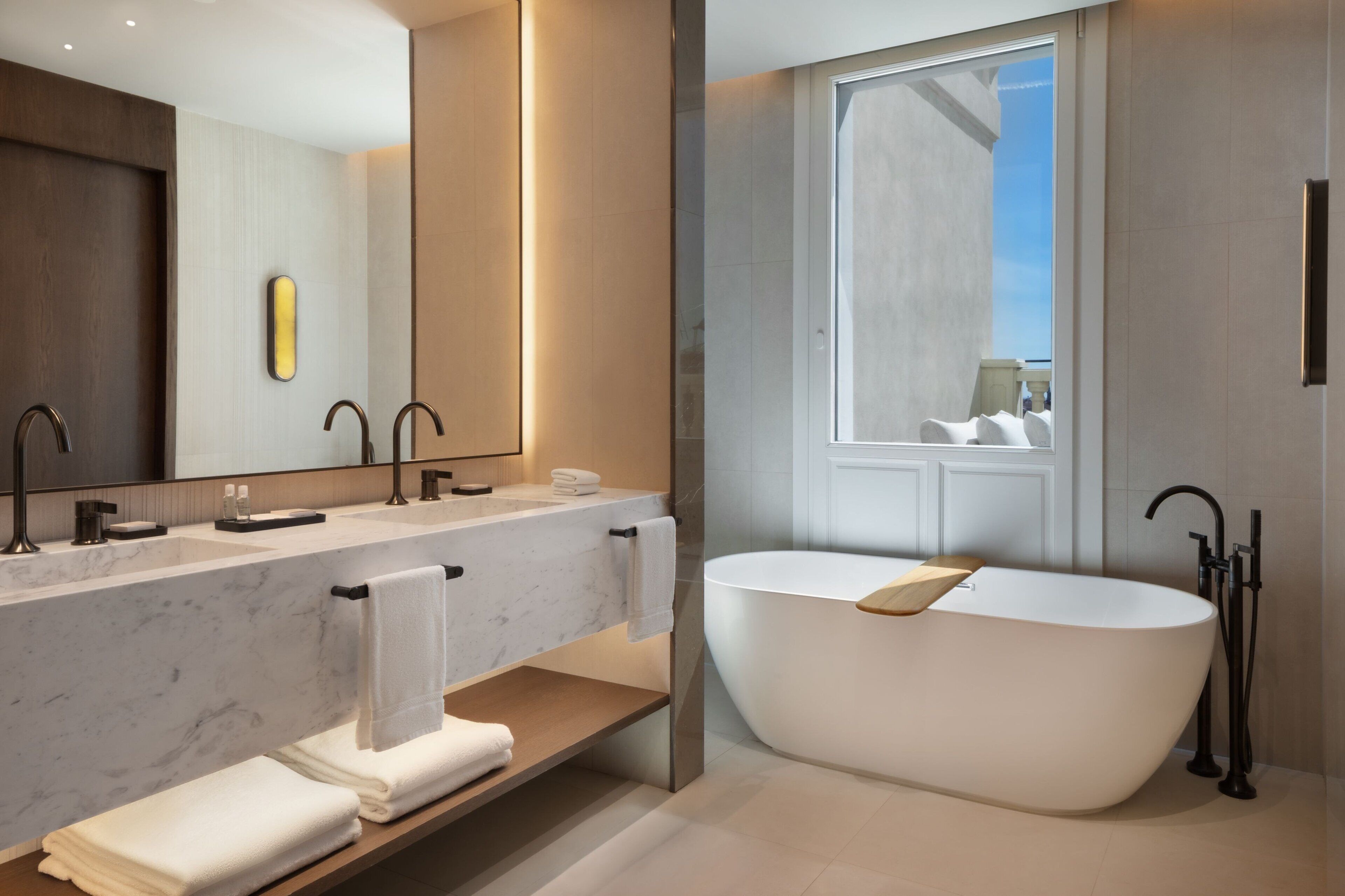 Ein modernes Badezimmer mit einer freistehenden Badewanne, zwei Waschbecken und einem großen Spiegel.