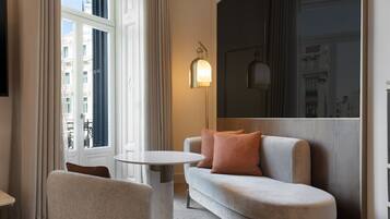 Une chambre d’hôtel moderne, équipée d’un canapé, d’une petite table ronde et d’un lampadaire.