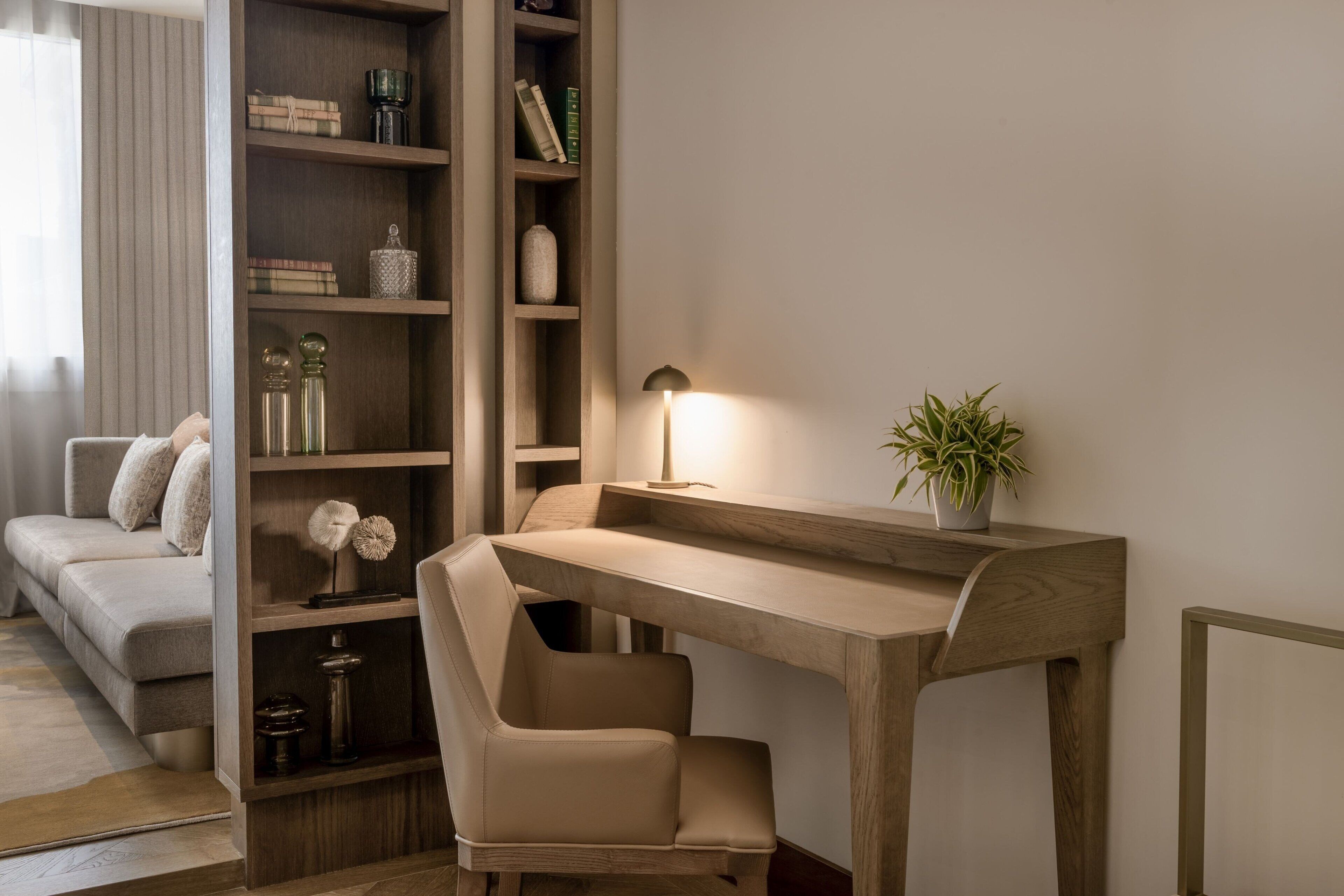 A modern living room with a wooden desk, a comfortable sofa, and a bookshelf.