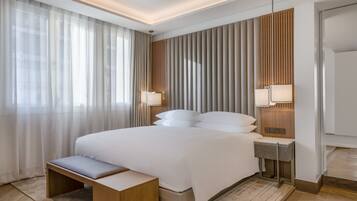 Een moderne hotelkamer met een groot bed, bedlampen, een bankje en een wand van hout.