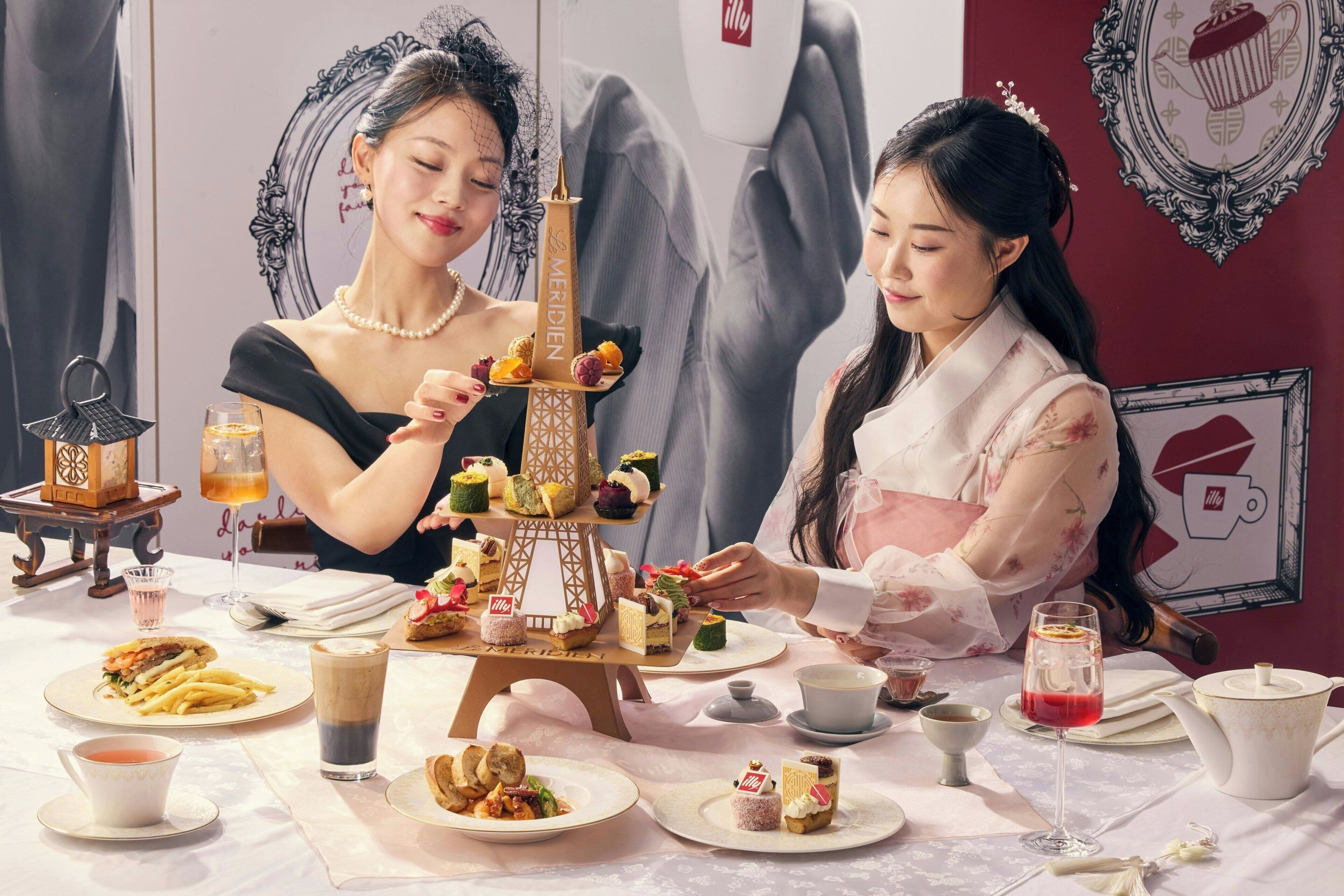 A table set with various food items and drinks, a decorative Eiffel Tower centerpiece, and a teapot.
