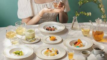 A table set with various dishes and drinks, including a pitcher of tea, a glass of white wine, and plates of food.