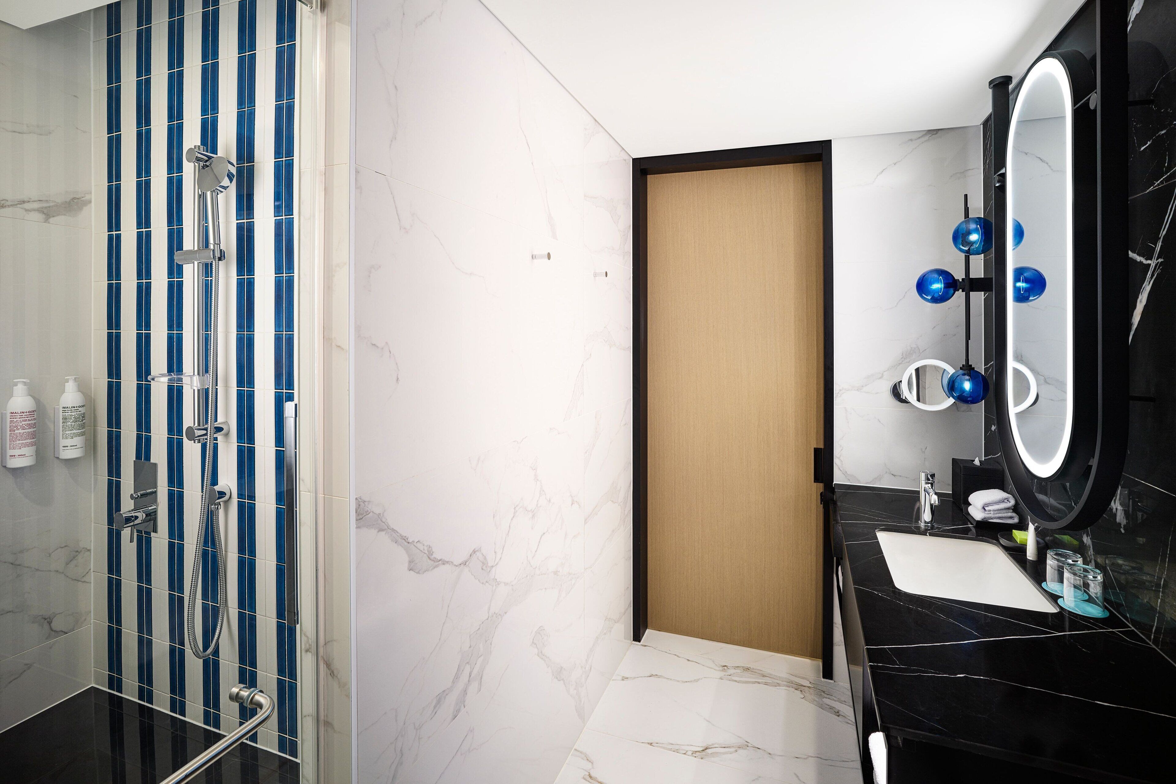 A modern bathroom with a shower, a toilet, and a sink with a mirror.