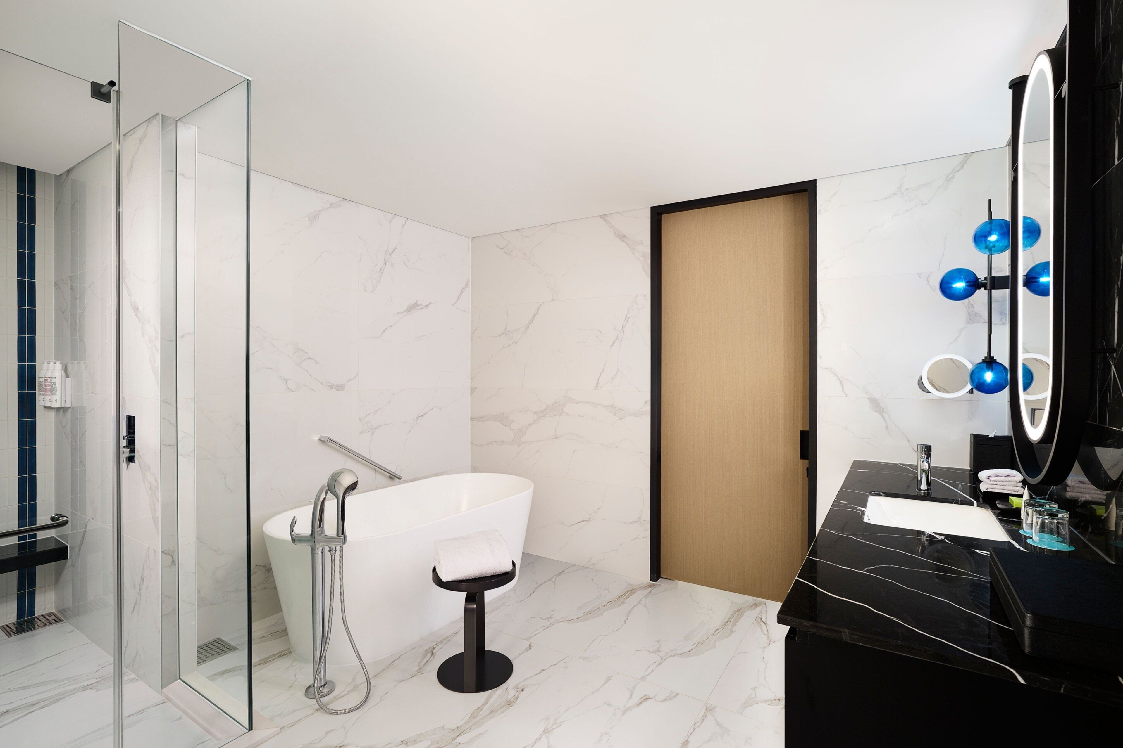 Un baño moderno con ducha de vidrio, bañera independiente y tocador negro con espejo.
