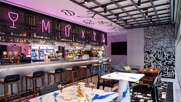 A bar area with a neon sign, bar stools, and a table with a stack of wooden blocks.