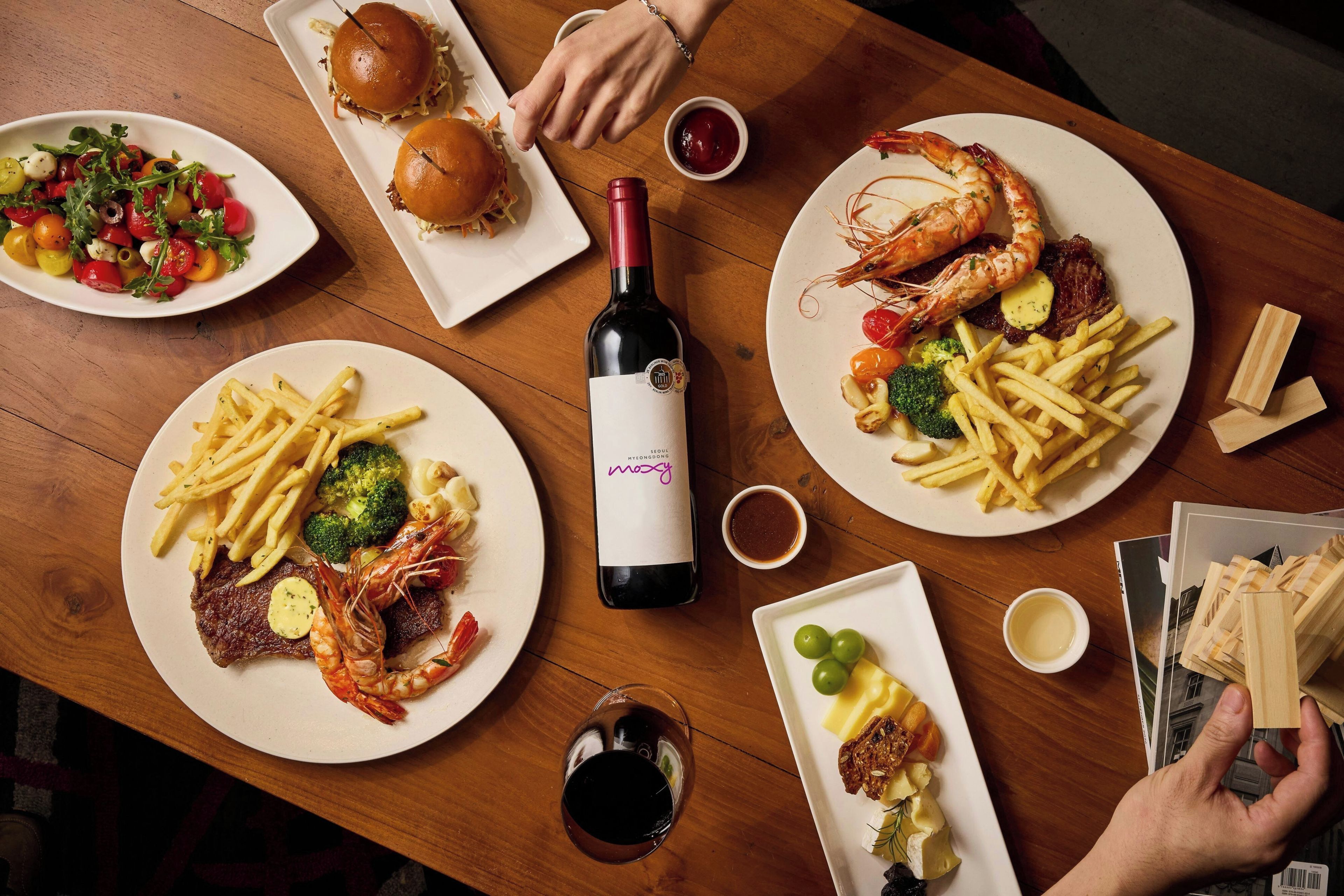 Una mesa de comedor con diversos platos, incluyendo camarones, carne y papas fritas.