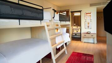 A compact hotel room with bunk beds, a small desk, a mirror, and a red rug.