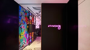 A hallway with colorful graffiti art on the walls and a neon sign that reads "mozy". - Moxy Seoul Myeongdong (Seoul)