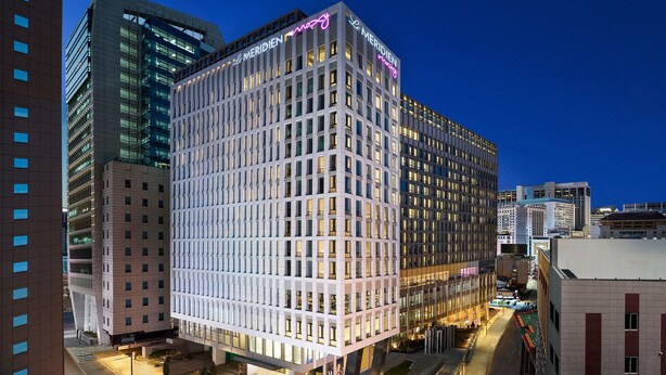 A modern hotel with a grid-like facade, large windows, and a neon sign. - Moxy Seoul Myeongdong (Seoul)