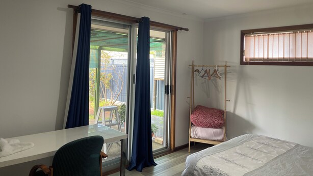 Une chambre à coucher avec un lit, un bureau et une fenêtre avec des rideaux.