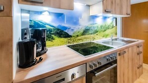 Une cuisine moderne dotée d’une hotte en acier inoxydable, d’une cuisinière encastrée, d’un évier et d’une machine à café.