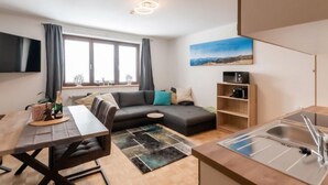 Un appartement moderne comprenant un coin repas, un canapé, une cuisine et une grande fenêtre avec des rideaux.