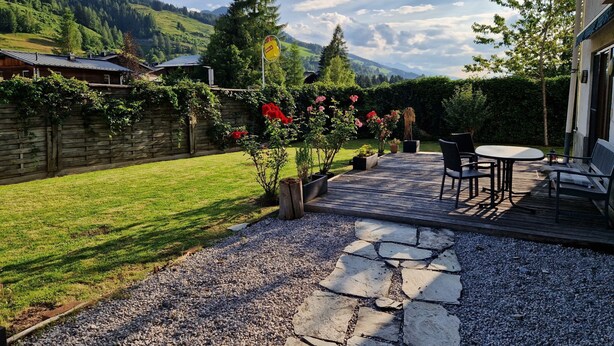 Une terrasse avec un chemin de pierre menant à un espace détente équipé d’une table et de chaises.