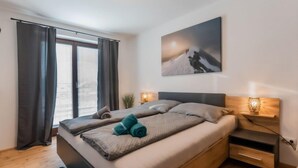 Une chambre à coucher moderne avec un lit, des tables de chevet et une fenêtre avec des rideaux.