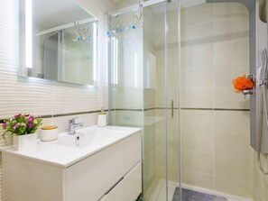 A bathroom with a white vanity, a glass shower enclosure, and a mirror above the vanity. - Ciudad Jardin by Interhome (Oropesa del Mar)