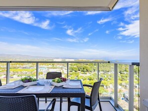A balcony table set with plates, glasses, and a fruit bowl, overlooking a scenic landscape with buildings and greenery. - Ciudad Jardin by Interhome (Oropesa del Mar)