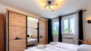 A bedroom with a large bed, wooden wardrobe, and a window with curtains.