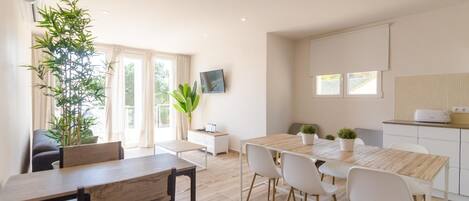 Una cocina moderna con zona de comedor, que incluye una mesa y sillas de madera, una pequeña isla de cocina y una planta grande en maceta.